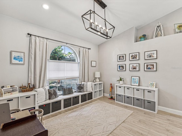 interior space with baseboards, vaulted ceiling, an inviting chandelier, and wood finished floors