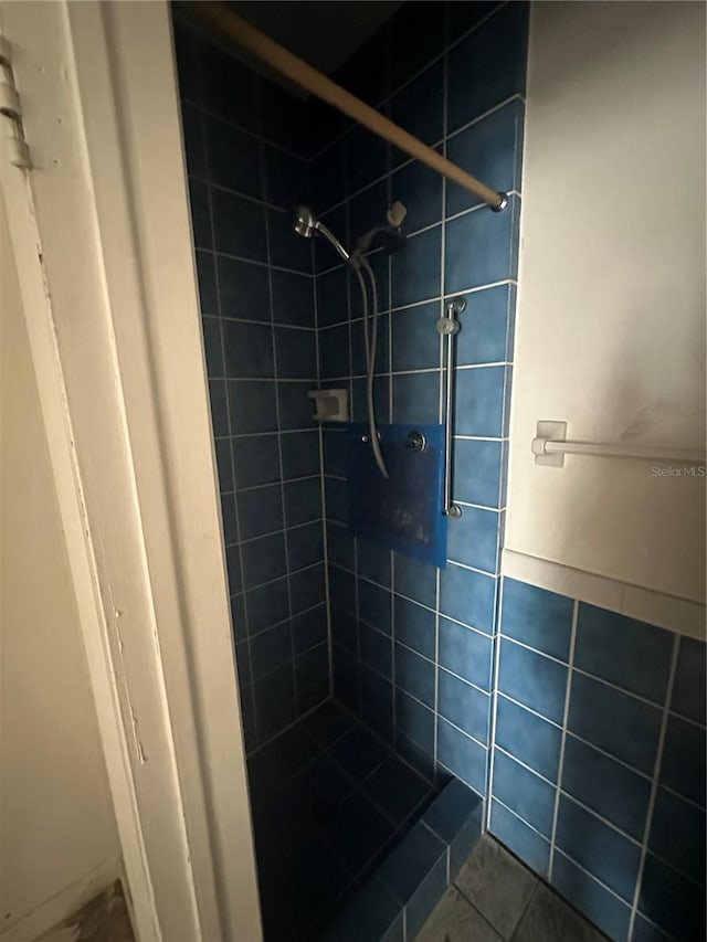 bathroom with tiled shower and tile patterned floors