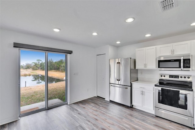 kitchen featuring a water view, appliances with stainless steel finishes, white cabinets, and light hardwood / wood-style flooring