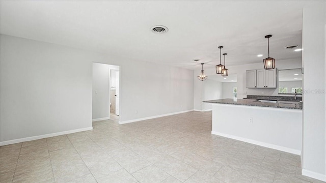 kitchen with decorative light fixtures, dark stone counters, and kitchen peninsula