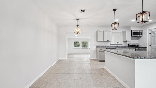 kitchen featuring white cabinets, stainless steel appliances, hanging light fixtures, and dark stone counters