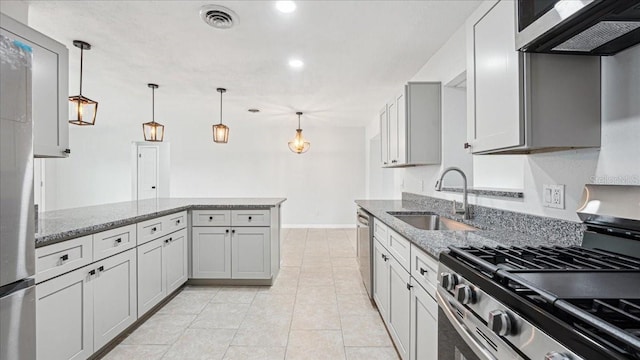 kitchen featuring appliances with stainless steel finishes, sink, pendant lighting, and light stone counters