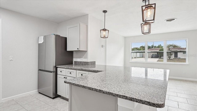 kitchen with white cabinetry, pendant lighting, stainless steel refrigerator, and kitchen peninsula