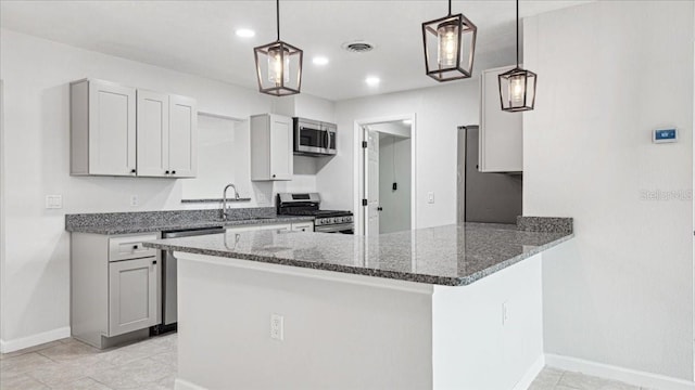 kitchen featuring sink, dark stone countertops, stainless steel appliances, decorative light fixtures, and kitchen peninsula