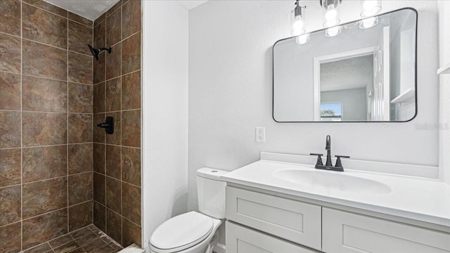 bathroom with vanity, a tile shower, and toilet