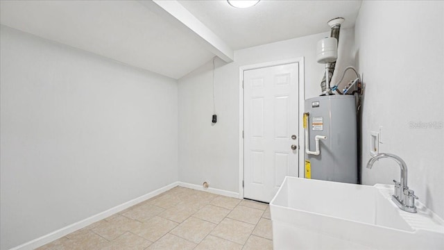 clothes washing area with water heater, light tile patterned flooring, and sink