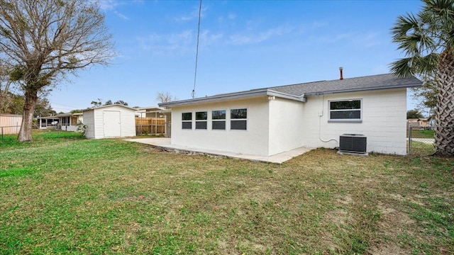 rear view of property with a storage shed, a lawn, and central air condition unit