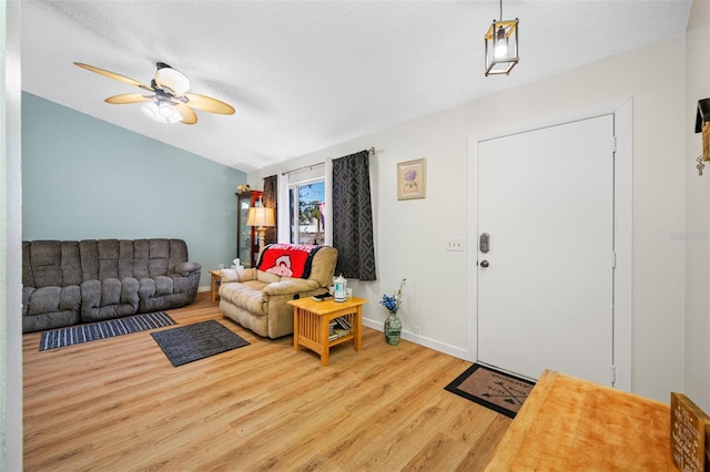 living room featuring ceiling fan, lofted ceiling, light hardwood / wood-style floors, and a textured ceiling