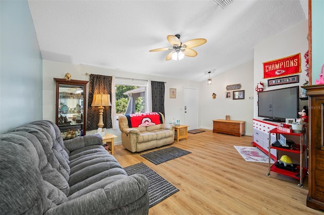 living room featuring wood-type flooring, vaulted ceiling, ceiling fan, and a textured ceiling