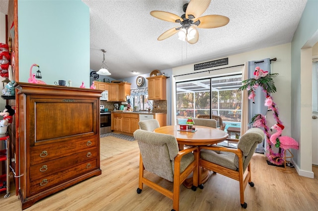 dining space with ceiling fan, a textured ceiling, and light wood-type flooring