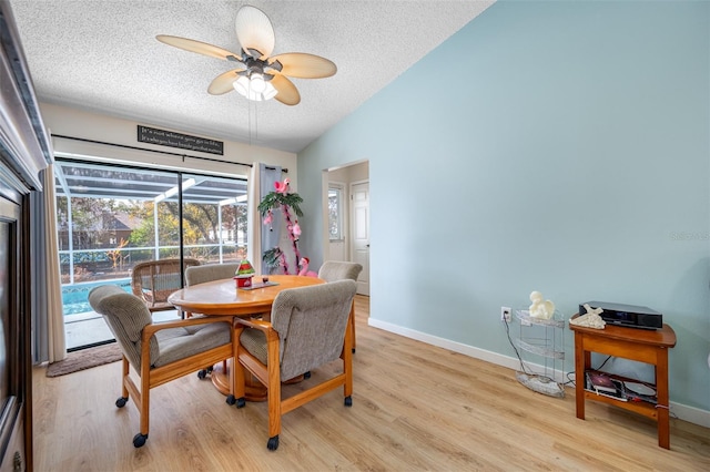 dining area with ceiling fan, lofted ceiling, a textured ceiling, and light hardwood / wood-style floors