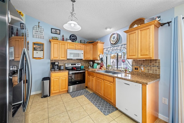 kitchen with lofted ceiling, sink, light tile patterned floors, stainless steel appliances, and decorative light fixtures