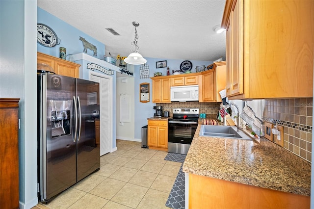 kitchen with light tile patterned flooring, sink, vaulted ceiling, pendant lighting, and stainless steel appliances