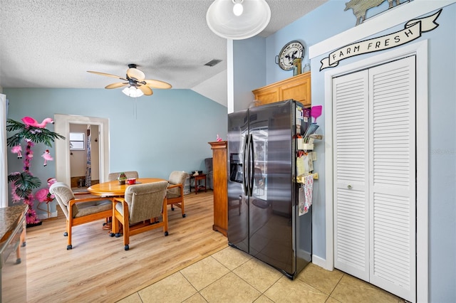 kitchen with lofted ceiling, light tile patterned floors, a textured ceiling, and stainless steel fridge with ice dispenser