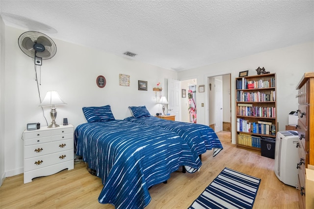 bedroom with light hardwood / wood-style floors and a textured ceiling