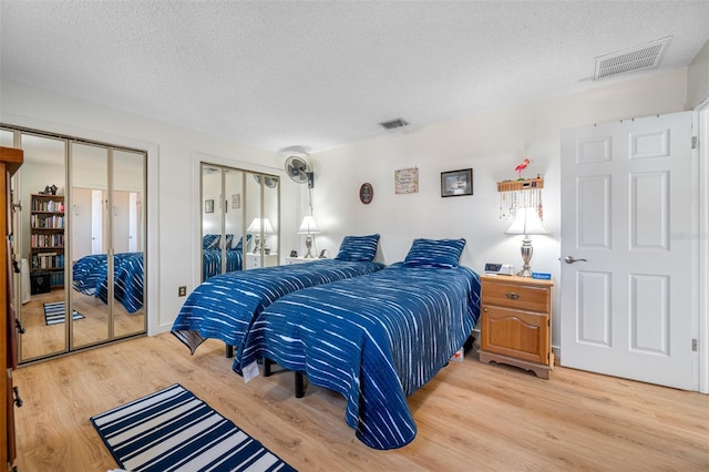 bedroom featuring two closets, hardwood / wood-style floors, and a textured ceiling