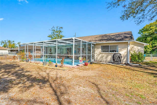 back of property with a fenced in pool, a yard, and glass enclosure