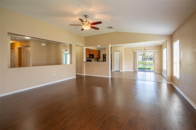 unfurnished living room featuring baseboards, visible vents, dark wood finished floors, vaulted ceiling, and ceiling fan with notable chandelier