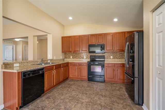 kitchen with vaulted ceiling, black appliances, brown cabinetry, and a sink