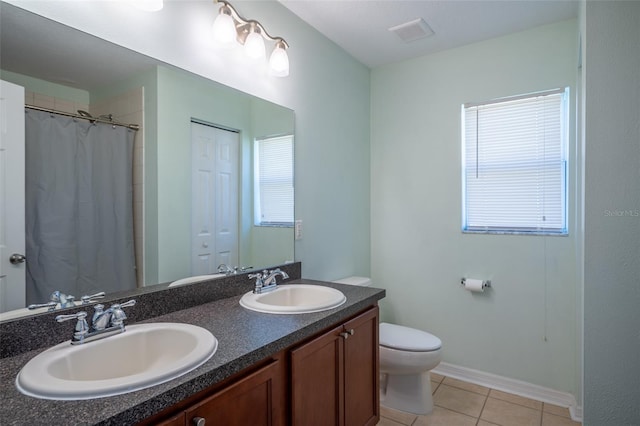 bathroom featuring toilet, tile patterned flooring, double vanity, and a sink