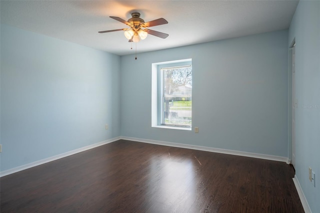 empty room with dark wood finished floors, baseboards, and ceiling fan