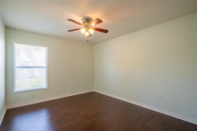 unfurnished room featuring dark wood finished floors, baseboards, and ceiling fan