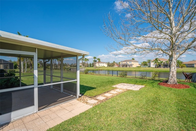 view of yard featuring a sunroom, a water view, and fence