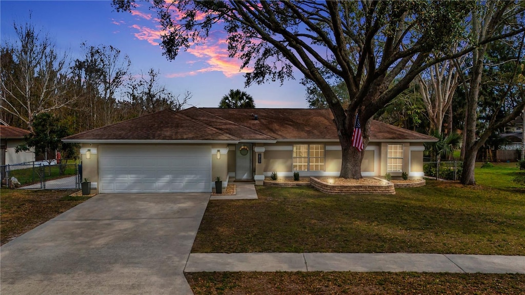 ranch-style home with a garage and a lawn