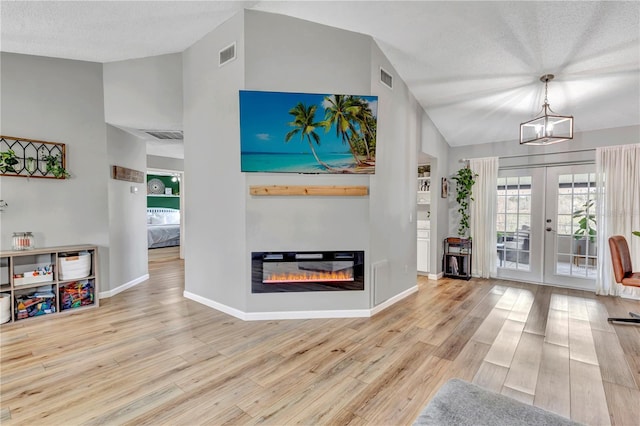 living room with french doors, a textured ceiling, and light wood-type flooring