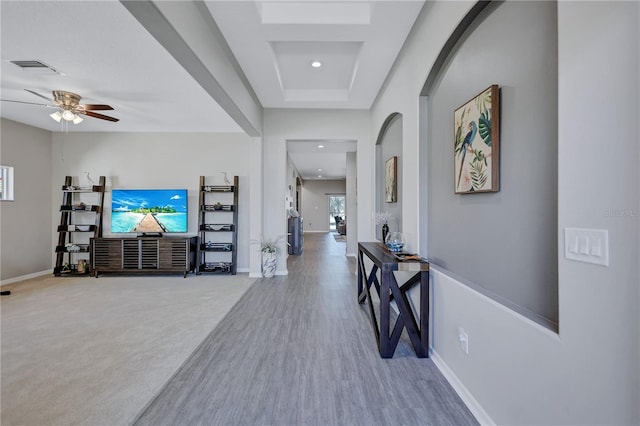 corridor with wood finished floors, baseboards, visible vents, recessed lighting, and arched walkways