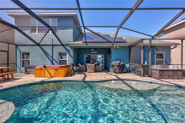 outdoor pool with a patio area, glass enclosure, a hot tub, and a ceiling fan