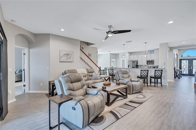 living room featuring stairway, recessed lighting, arched walkways, and light wood-type flooring