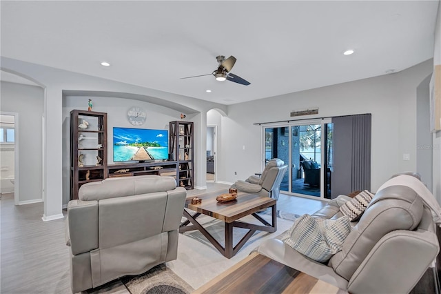 living area with recessed lighting, arched walkways, and light wood finished floors