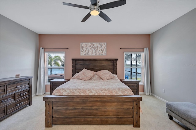 bedroom featuring light colored carpet, baseboards, and multiple windows