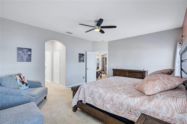 bedroom with a ceiling fan, baseboards, arched walkways, a closet, and light colored carpet