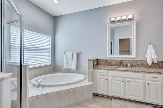 full bath with vanity, a garden tub, and a shower stall