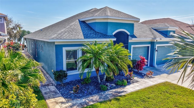 view of front facade with a shingled roof, concrete driveway, an attached garage, and stucco siding