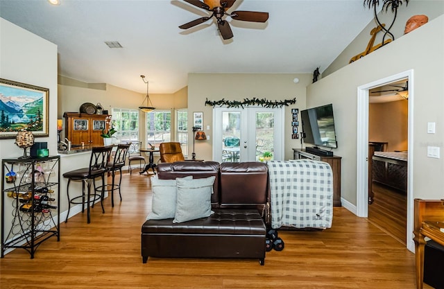 living room featuring vaulted ceiling, light hardwood / wood-style floors, french doors, and ceiling fan