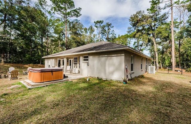 back of property with a hot tub, a patio, central AC unit, and a lawn