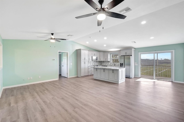 unfurnished living room with ceiling fan, vaulted ceiling, and light wood-type flooring