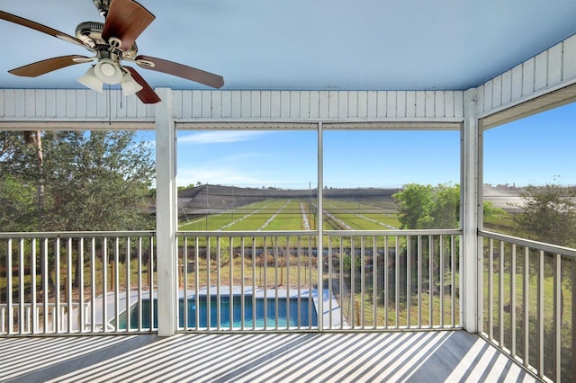 unfurnished sunroom featuring ceiling fan, a healthy amount of sunlight, and a rural view