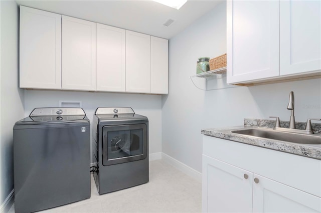 clothes washing area featuring cabinets, sink, and washer and clothes dryer