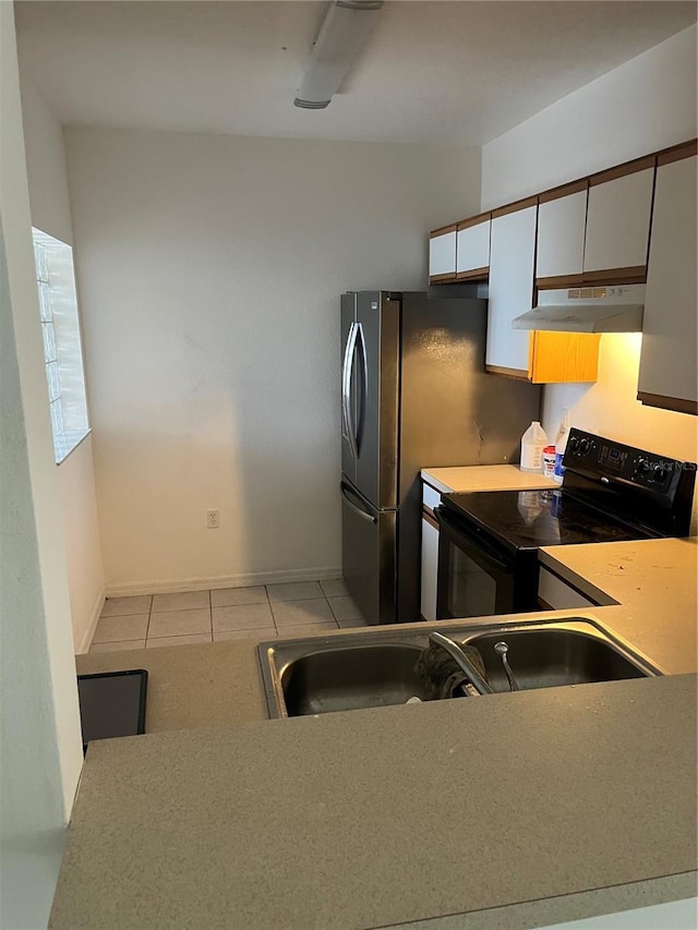 kitchen featuring white cabinetry, sink, stainless steel fridge, light tile patterned floors, and electric range