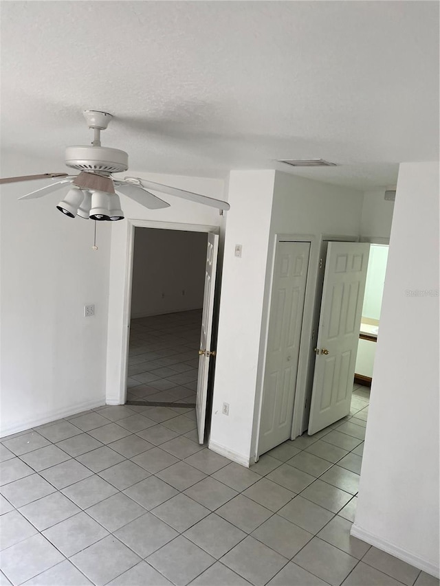 tiled spare room featuring a textured ceiling and ceiling fan