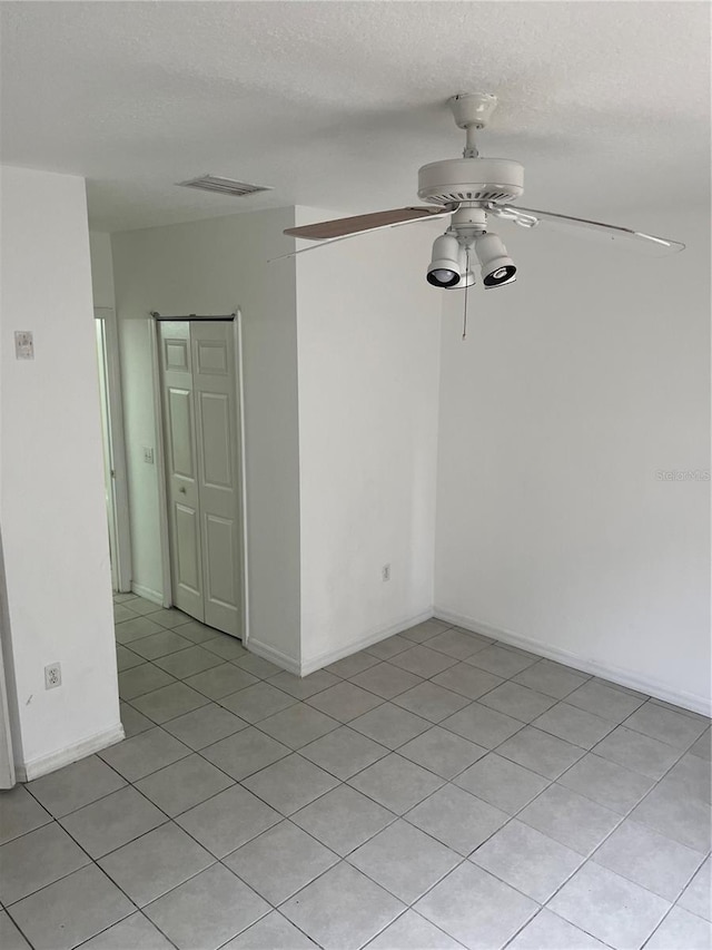 empty room with ceiling fan and a textured ceiling