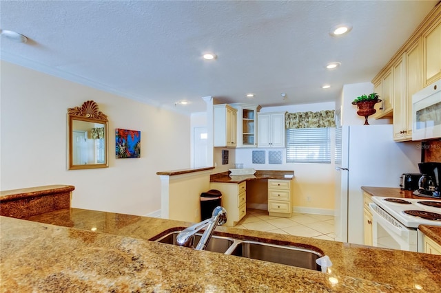 kitchen with light tile patterned flooring, sink, white appliances, a textured ceiling, and cream cabinetry