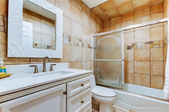 full bathroom with tile walls, vanity, enclosed tub / shower combo, and toilet