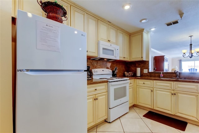 kitchen featuring light tile patterned floors, white appliances, hanging light fixtures, and cream cabinetry