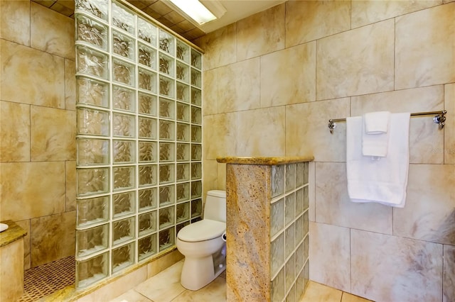 bathroom featuring walk in shower, tile patterned floors, toilet, and tile walls