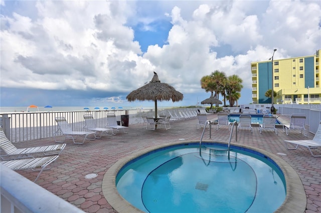 view of swimming pool featuring a patio, a water view, and a community hot tub